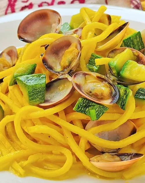 Tonnarelli con vongole e zucchine serviti in un piatto chiaro