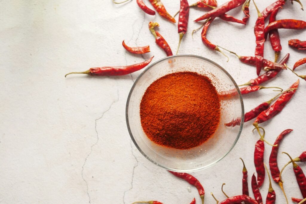 Peperoncino rosso essiccato e in polvere in una ciotola, una delle spezie essenziali nella cucina italiana, utilizzata per dare un tocco piccante ai piatti.